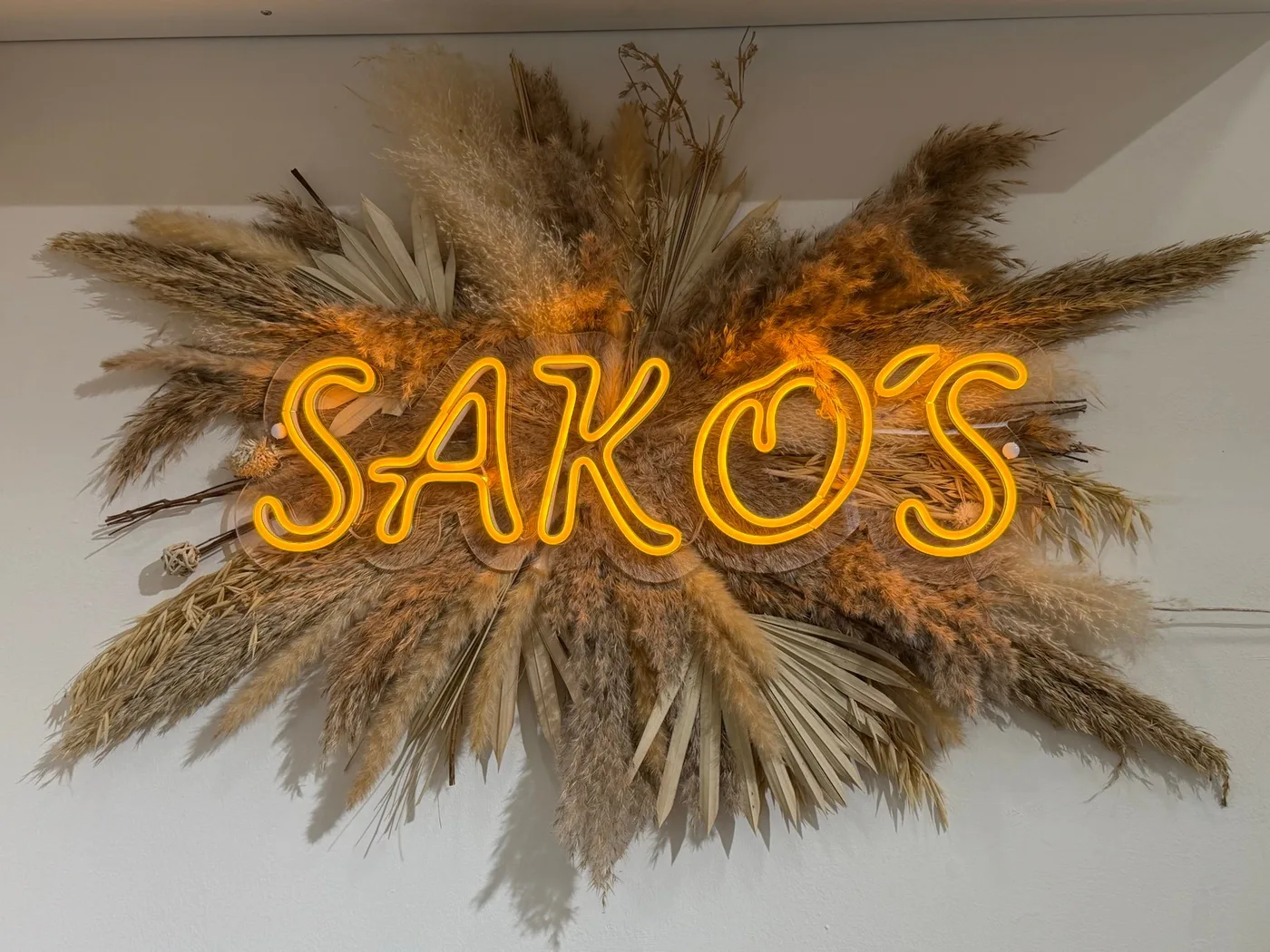 Cartel luminoso de Sakos con flores secas en la tienda